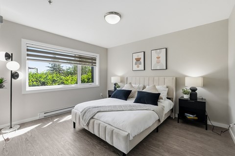A bedroom with a large bed and a window with blinds.