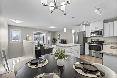 A modern kitchen with a dining table set for two.