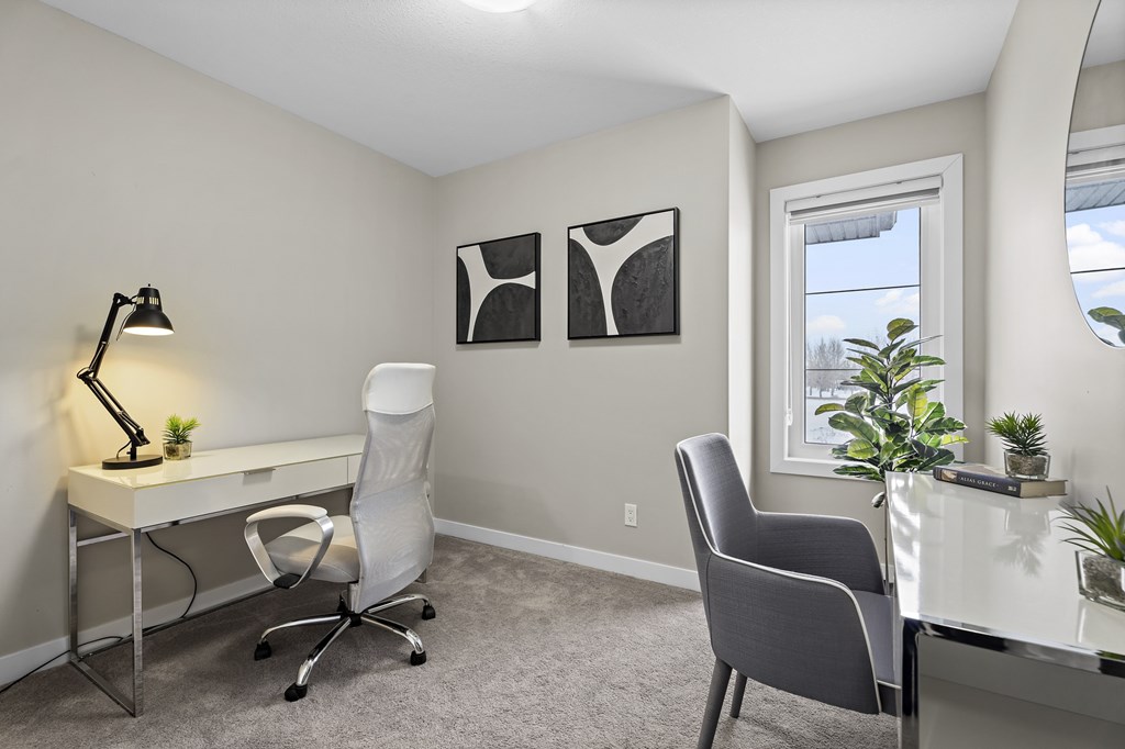 A room with a desk, chair, and two framed pictures on the wall.