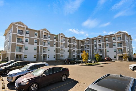 A parking lot with cars and apartment buildings in the background.