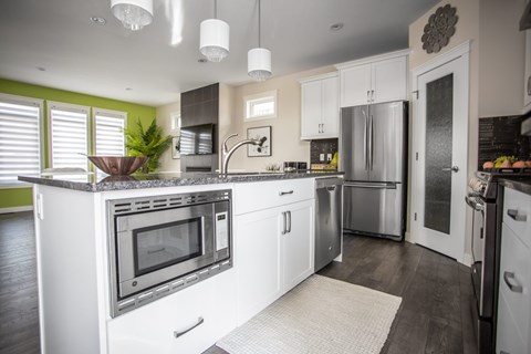 A modern kitchen with white cabinets and stainless steel appliances.