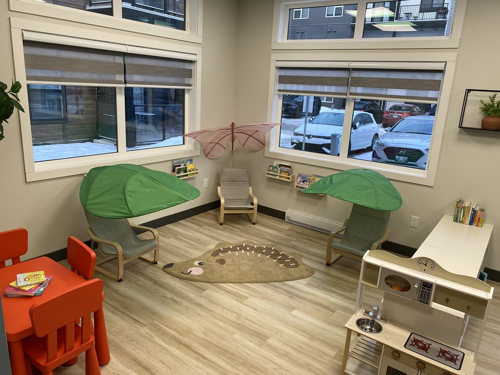 A room with a table, chairs, and a playpen.