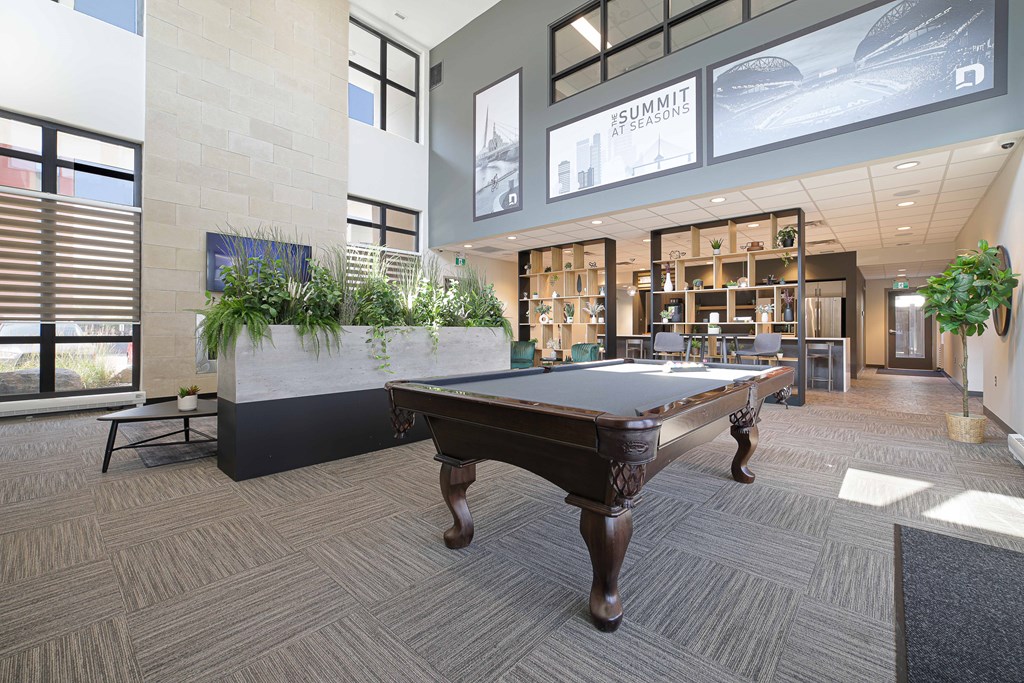 A room with a pool table and a plant on the side.