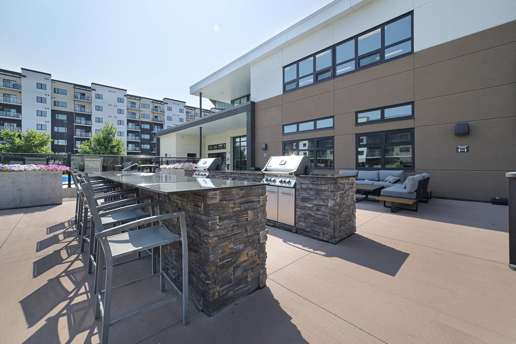 A modern outdoor seating area with a stone barrier and metal chairs.