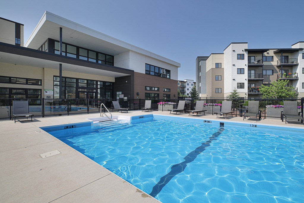 A large swimming pool in front of a building with apartment complexes in the background.