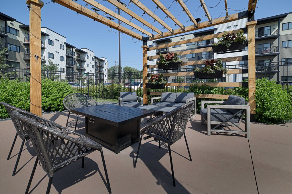 A patio with a table and chairs under a pergola.