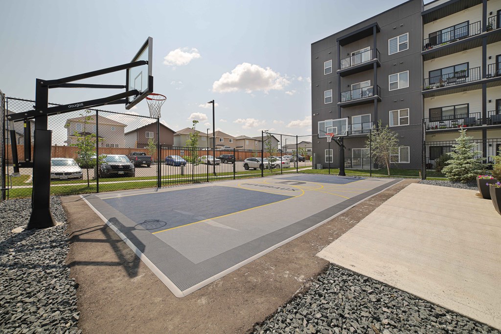 A basketball court is located in a courtyard surrounded by apartment buildings.