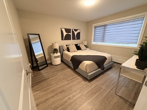 A bedroom with a bed, nightstand, and a mirror.