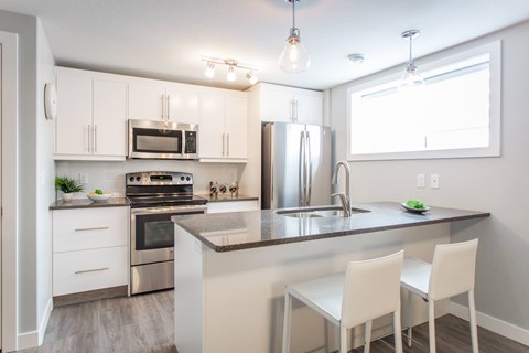 A kitchen with white cabinets and a granite countertop.