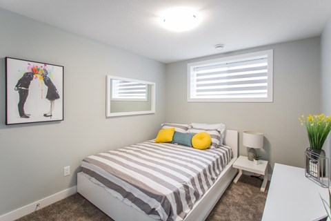 A bedroom with a bed, nightstand, and a painting on the wall.