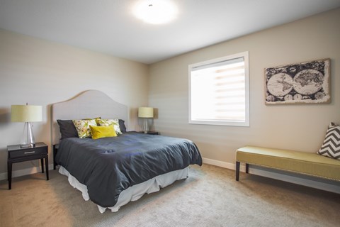 A bedroom with a bed, two lamps, a bench, and a picture on the wall.