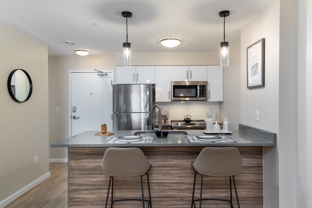 a kitchen with stainless steel appliances and a counter with two stools