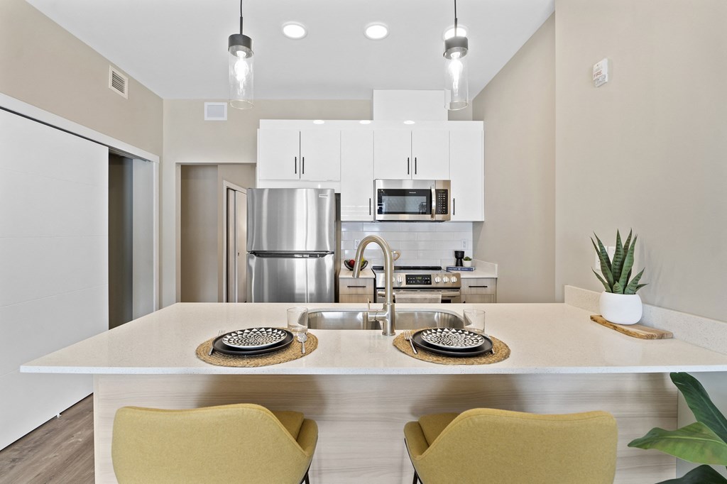 a kitchen with a large island with two chairs and a sink