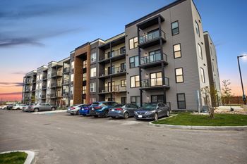 A modern apartment building with cars parked in front.
