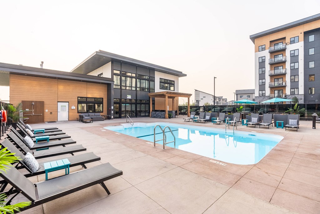 A pool area with sun loungers and a building in the background.