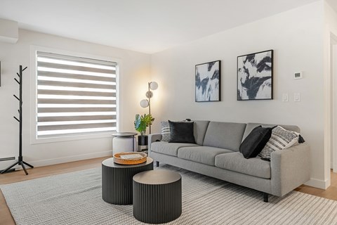 A living room with a grey couch, a small table, and two paintings on the wall.