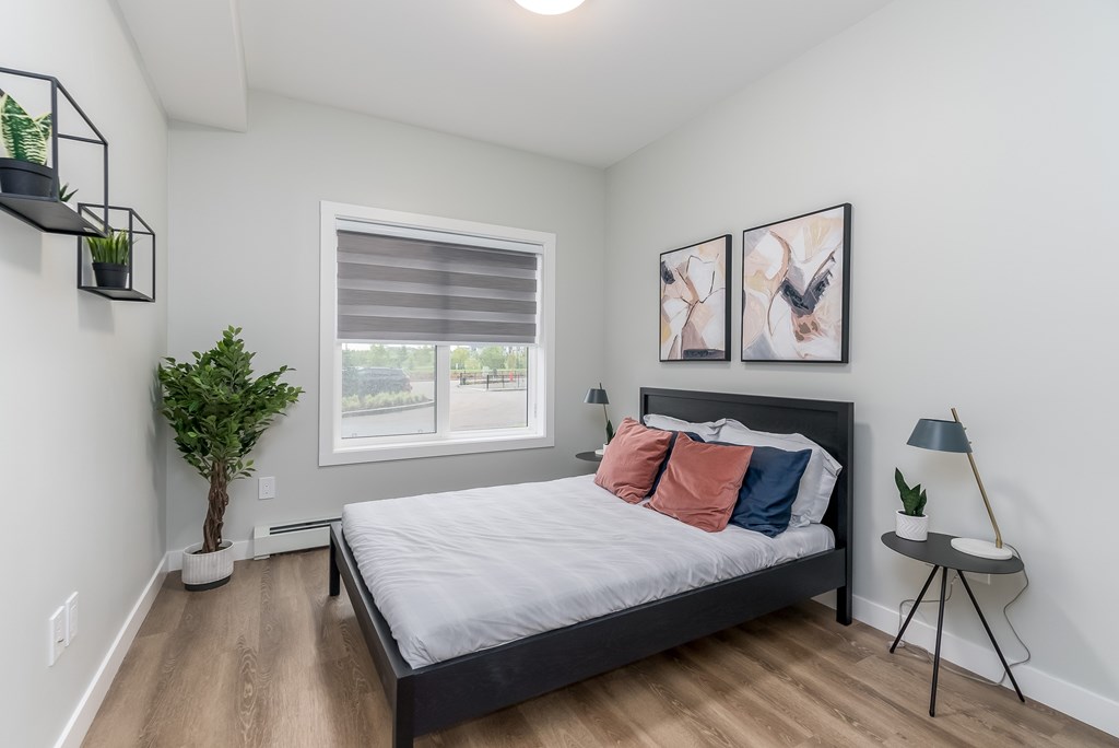 A bedroom with a bed, two lamps, and two pictures on the wall.