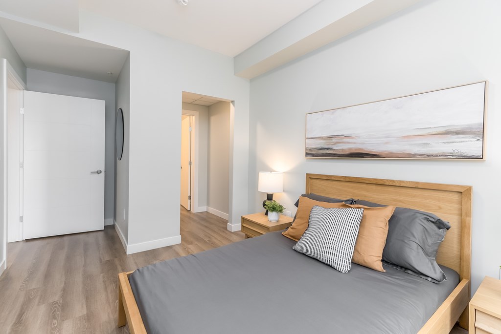 A bedroom with a large bed and a painting on the wall.