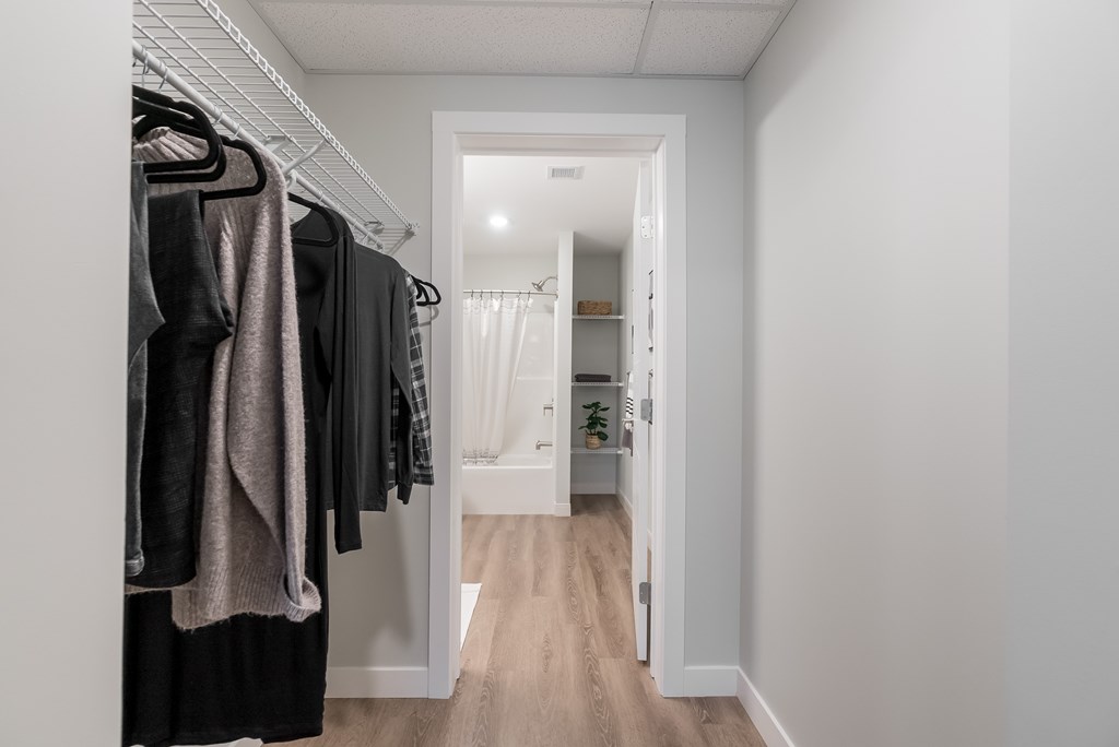 A hallway with a white door and a rack of clothes.