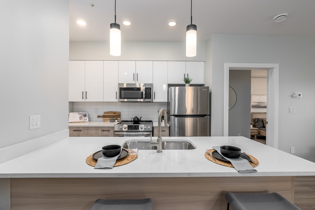 A modern kitchen with a white countertop and stainless steel appliances.