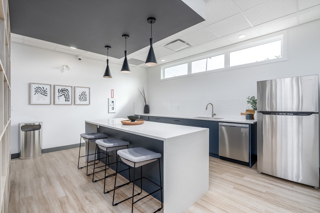 A modern kitchen with a white island and stools.