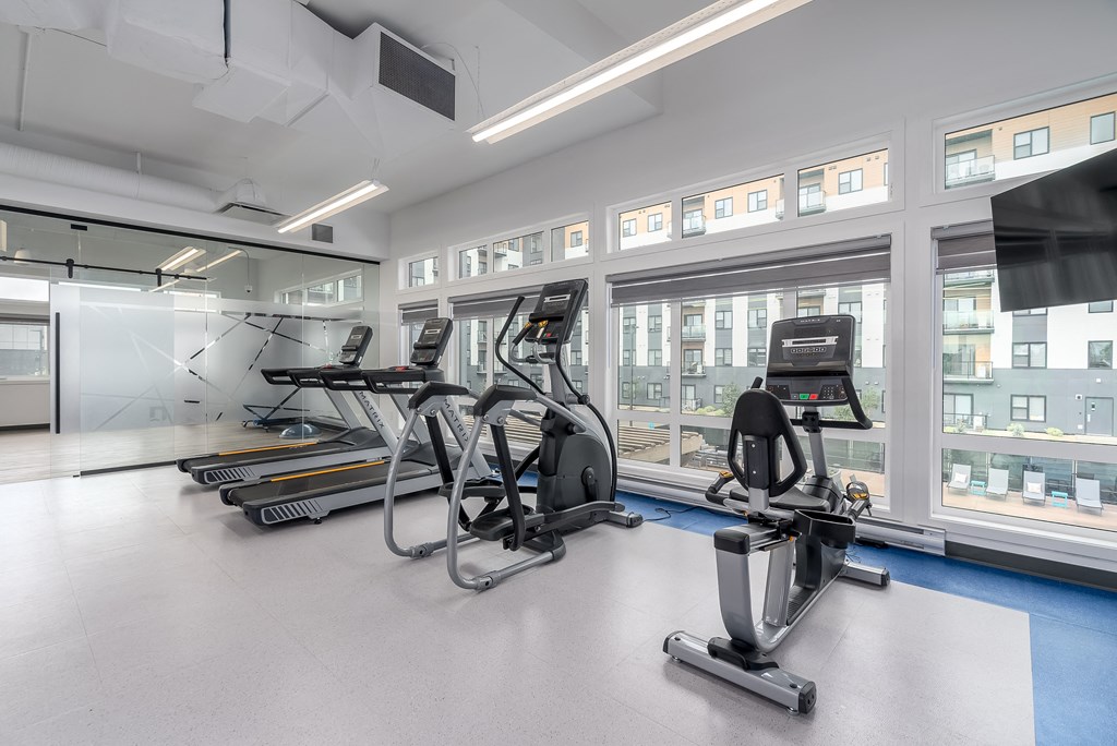 a gym with treadmills and other exercise equipment in a building with windows