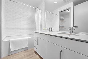 A white bathroom with a white tub, sink, and shower.at Raymond Block, Edmonton