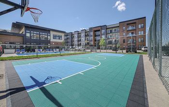 A basketball court is surrounded by apartment buildings.