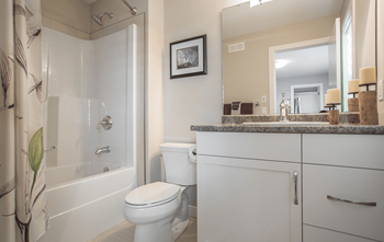 A white bathroom with a toilet, sink, and shower.