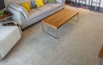 A grey couch with yellow pillows and a wooden coffee table.