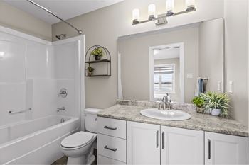 A white bathroom with a sink, mirror, and toilet.