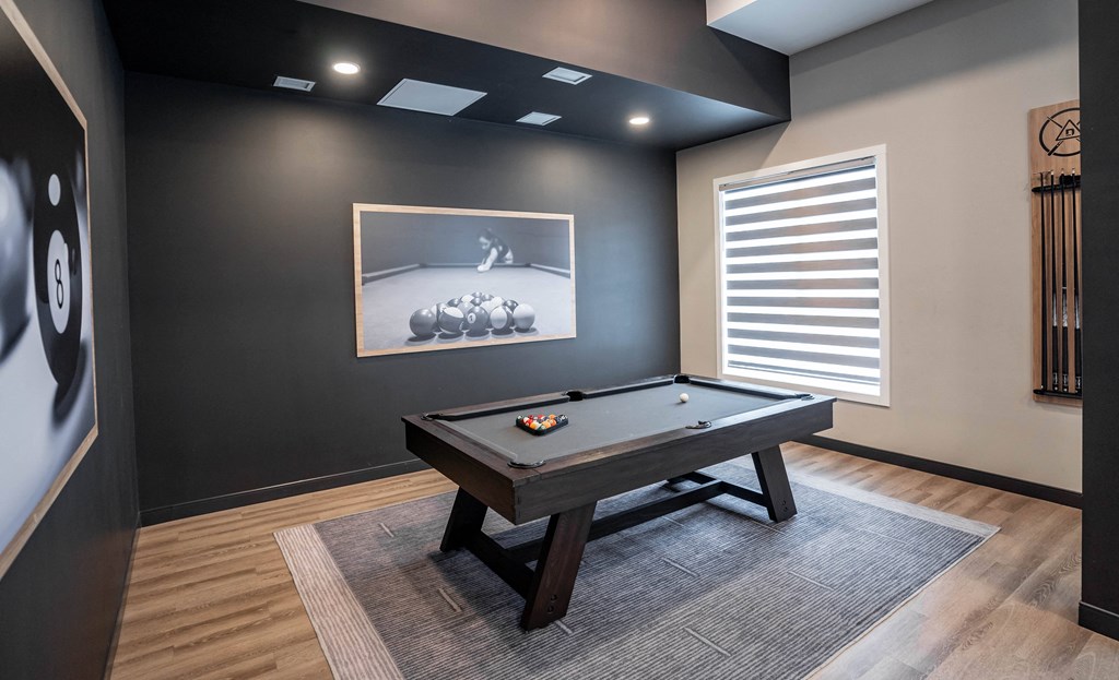 A pool table in a room with a picture of a pool player on the wall.