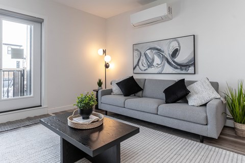 A living room with a grey couch, a black coffee table, and a large abstract painting on the wall.