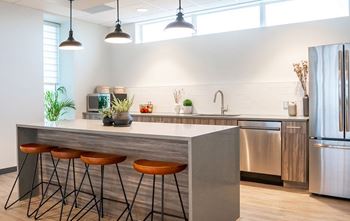 A modern kitchen with a bar stool and a refrigerator.