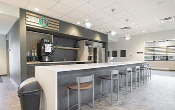 A Starbucks counter with stools and a trash can.