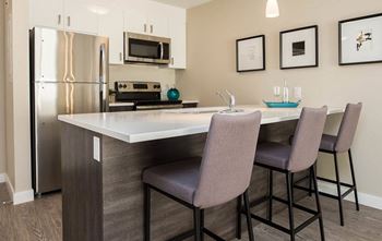 A kitchen with a refrigerator, microwave, oven, and a table with chairs.