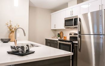 A modern kitchen with a stainless steel refrigerator, microwave, and oven.