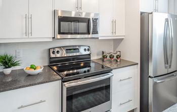 A modern kitchen with a stove, oven, microwave, and refrigerator.