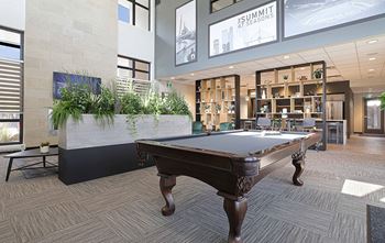 A pool table in a room with a plant on the side.