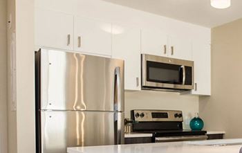 A kitchen with a stainless steel refrigerator and microwave above the stove.