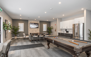 A pool table is in the middle of a room with a dining table and chairs.