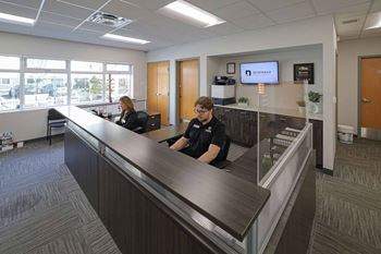 Two people sitting at a reception desk in a brightly lit office.at Skyway Apartments, Calgary Alberta