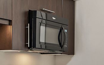 A black microwave oven is mounted on a wall.