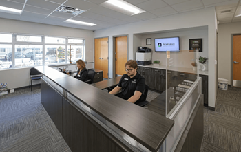 Two people sitting at a reception desk in a well-lit office.