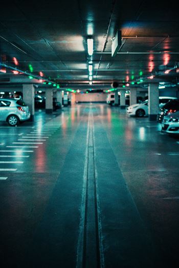 A parking garage with cars parked on both sides and a few cars driving through.at Raymond Block, Edmonton, AB T6E 3R7