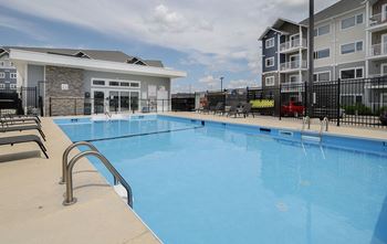A large outdoor swimming pool with a diving board and poolside seating.