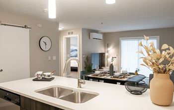 A modern kitchen with a white countertop and stainless steel sink.