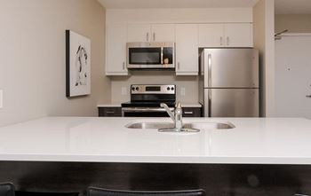 A modern kitchen with a white countertop and stainless steel appliances.