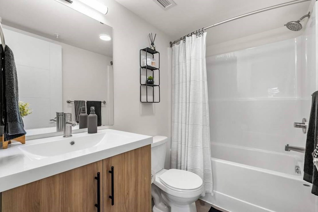 A white bathroom with a toilet, sink, and shower.at Skyway Apartments, Calgary, T3B 5V6