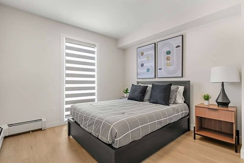 A bedroom with a large bed and a wooden nightstand.